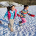 Two Girls Sledding in Snow
