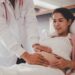 Doctor assisting a pregnant woman in a hospital bed.